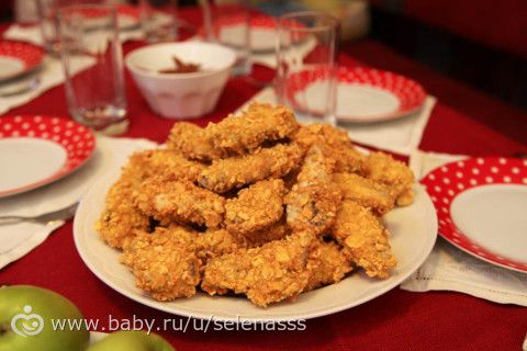 Куриные крилья или стрипсы в панировке.